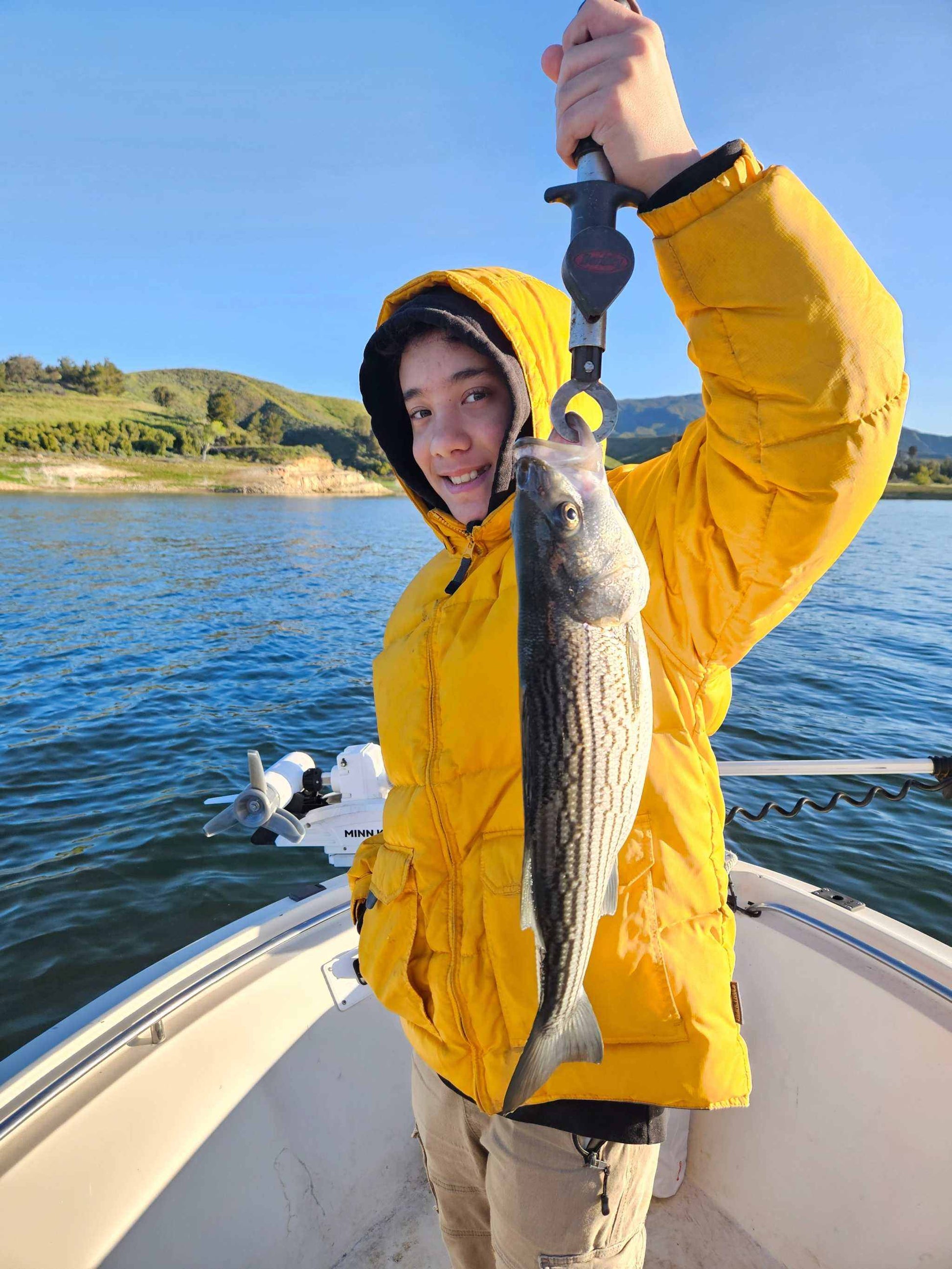 Guide Service, a young man in a yellow jacket holding a striper caught on an EZ U-Rig up