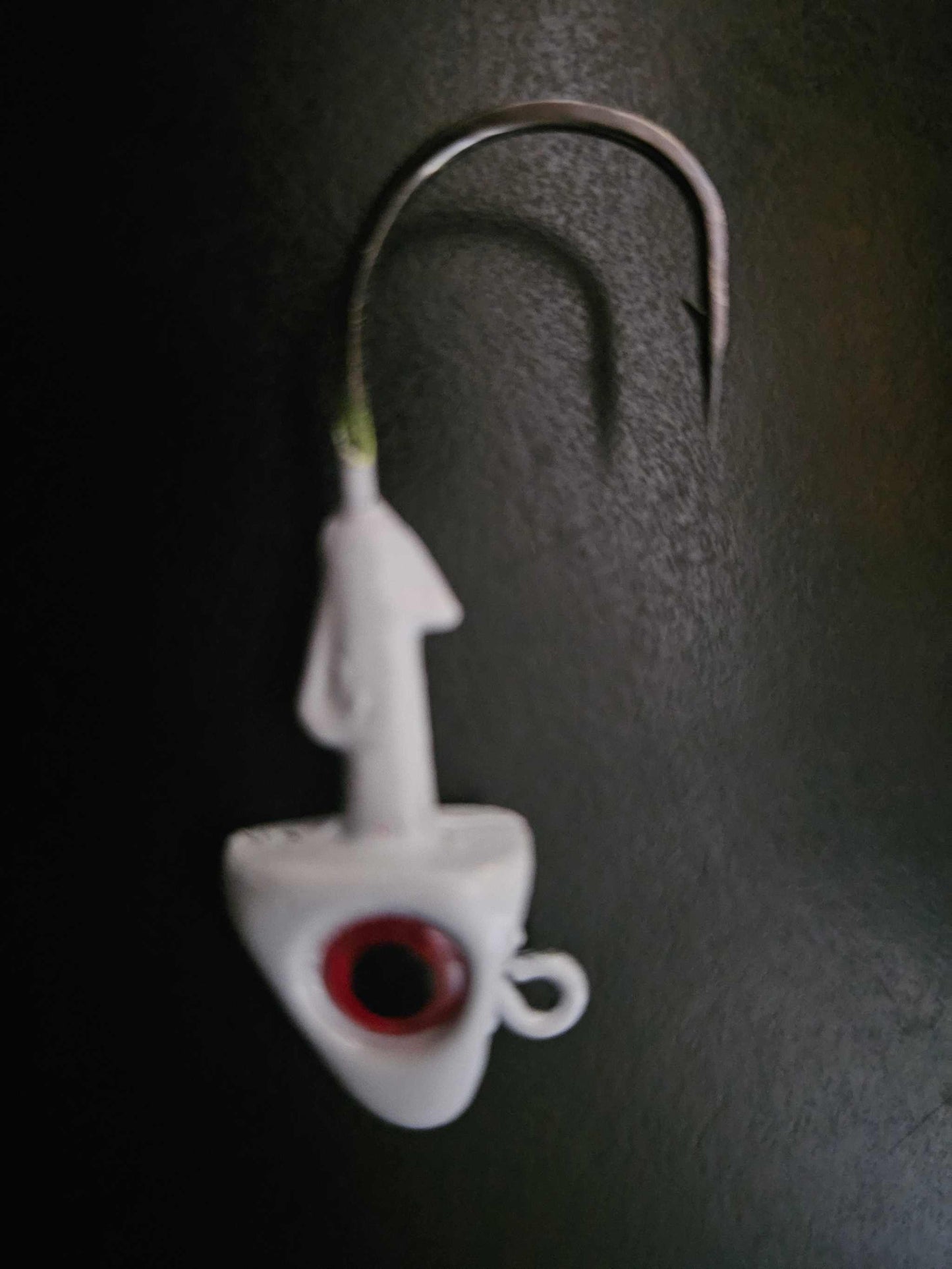 A picture showing 1 EZ Jig Head, ½ oz, White with Red eyes and a 3/0 Hook on a black background.