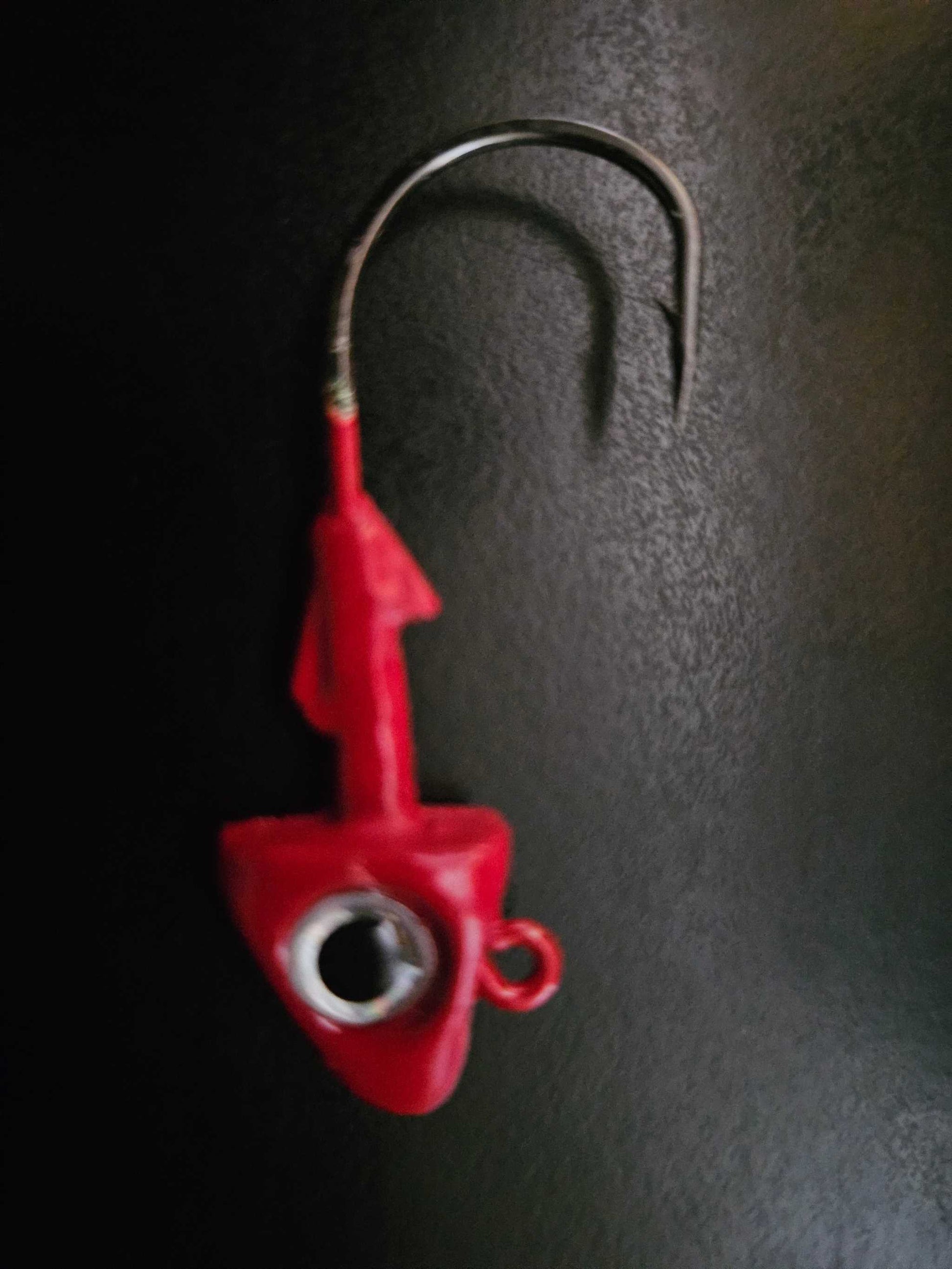 A picture showing 1 EZ Jig Head, ½ oz, Red with Silver eyes and a 3/0 Hook on a black background.